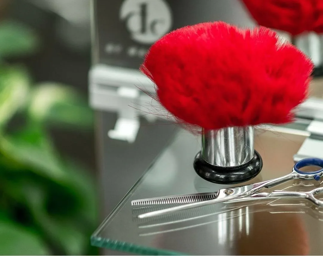 Roter Nackenpinsel und Schere vor dem DC-by-Waldera-Zeichen im Salon im Kino