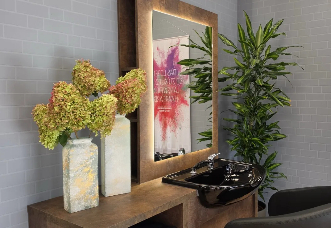 Waschplatz mit schwarzem Waschbecken und Pflanzen im Salon Luft Hoyerswerda